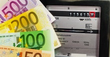 vier bunte Euroscheine aufgefächert vor einem analogen Ferraris-Stromzähler vier bunte Euroscheine aufgefächert vor einem analogen Ferraris-Stromzähler
